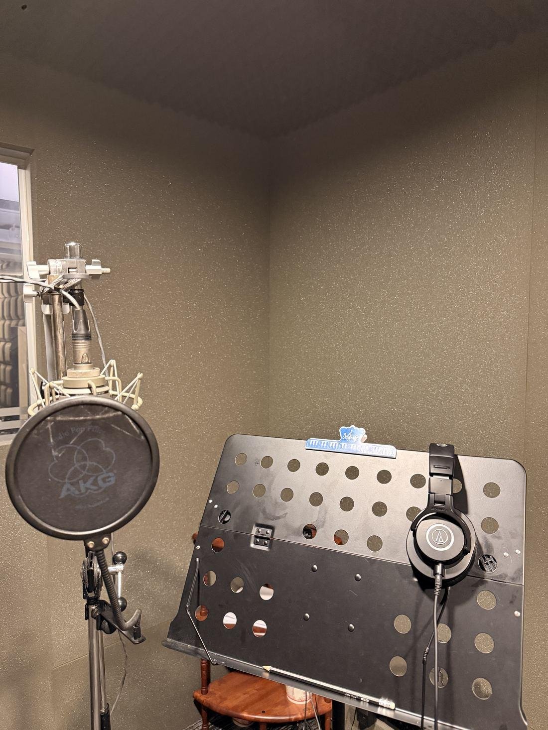 Vocal booth corner with headphones and sheet music stand
